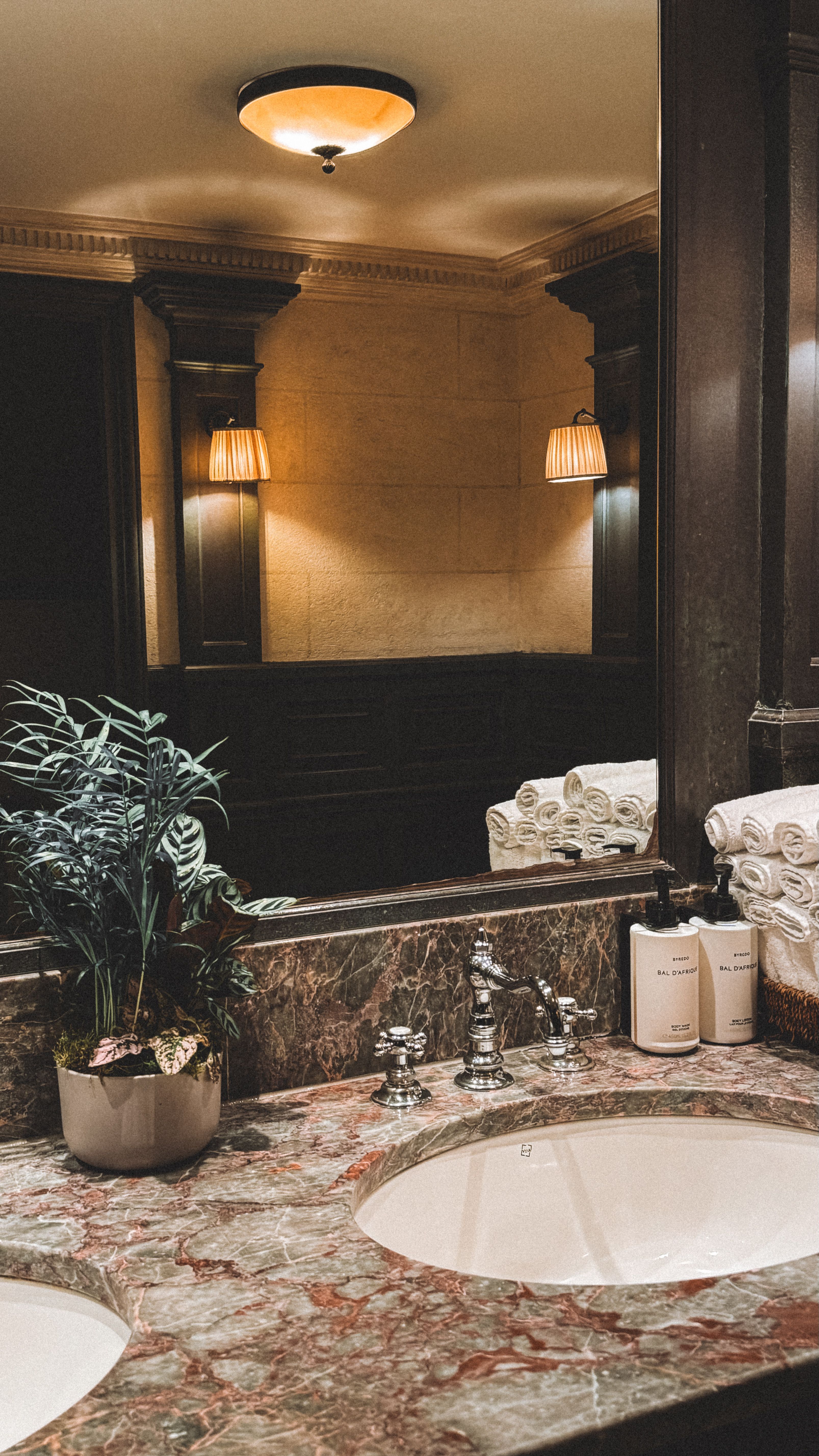Luxury dark marble bathroom renovation with ornate mirror and sconce lighting